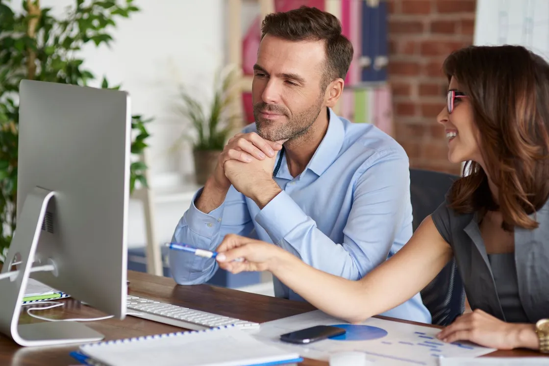 People meeting around laptops in an office.